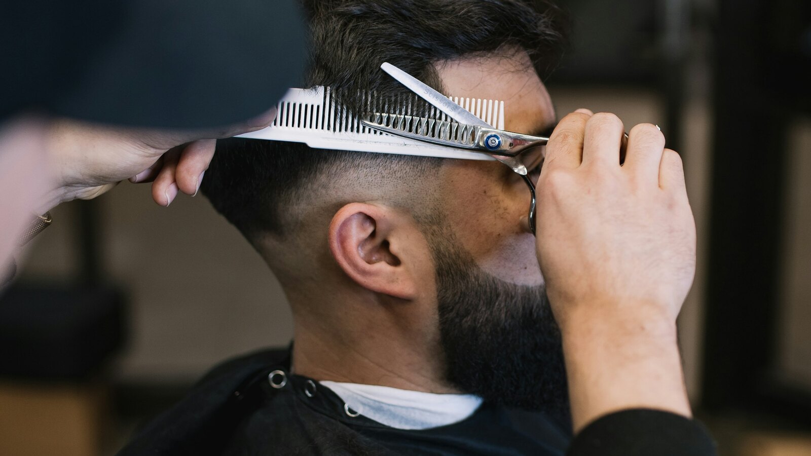 Barber cutting a mans hair with scissors